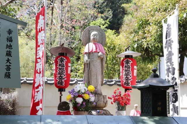 鈴虫寺の幸福地蔵を引き気味に撮影した写真。提灯や旗が写り、良縁祈願の雰囲気が伝わる構図