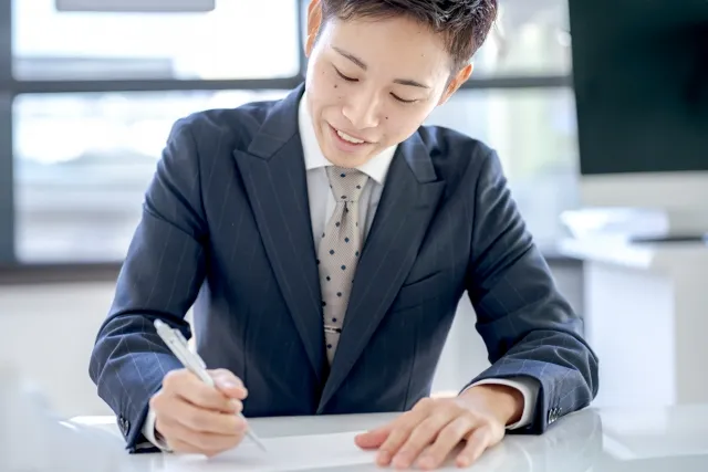 安心した表情で契約書にサインする男性。結婚相談所の制度に納得している様子