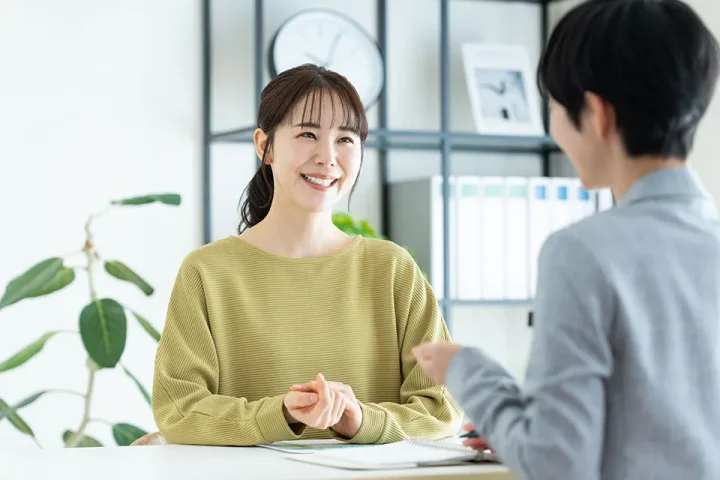 結婚相談所で婚活カウンセラーと笑顔で話す女性。安心して相談できる雰囲気を伝えるイメージ