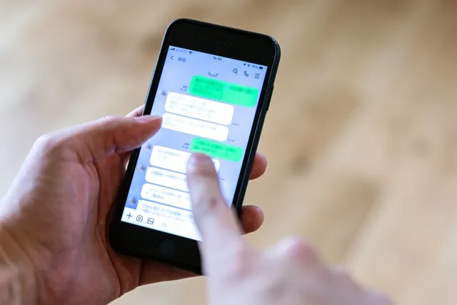 婚活男性が室内でスマホのLINEを操作する手元。LINE画面はぼかし処理され、婚活中のコミュニケーションをイメージできる写真。