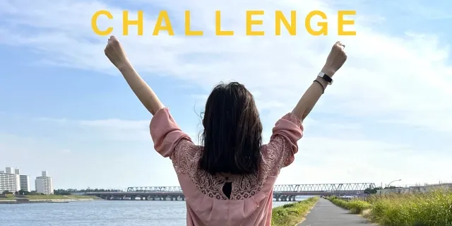 青空に両手をあげて挑戦を象徴する30代独身女性の後ろ姿。画像にはCHALLENGEの文字入り。