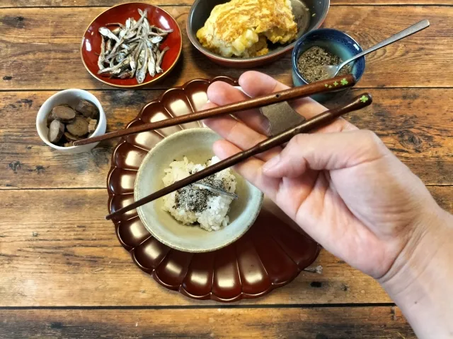 矯正箸を使って食事マナーの練習をする男性の手元と小鉢が並ぶ食卓