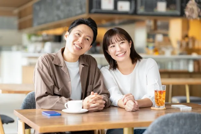 カフェで寄り添い笑顔で会話するカップル。真剣交際に向けて信頼を深める自然なコミュニケーションの様子を表現したイメージ