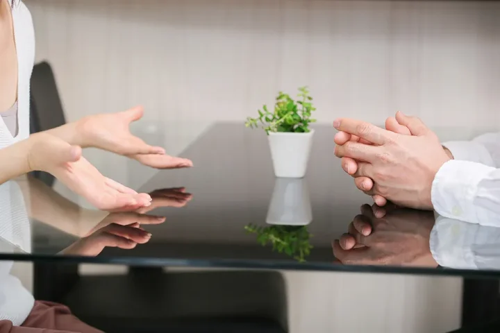 価値観の違いについて落ち着いて話し合う50代男女の手元と姿勢を写したシーン(顔なし)