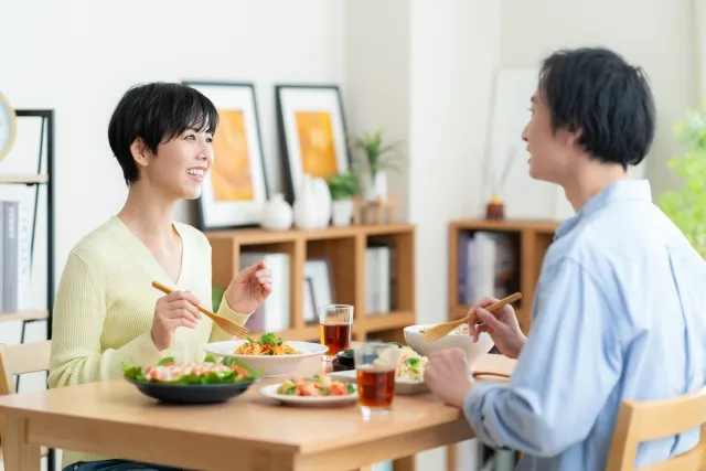 自宅で食卓を囲み笑顔で食事を楽しむ夫婦