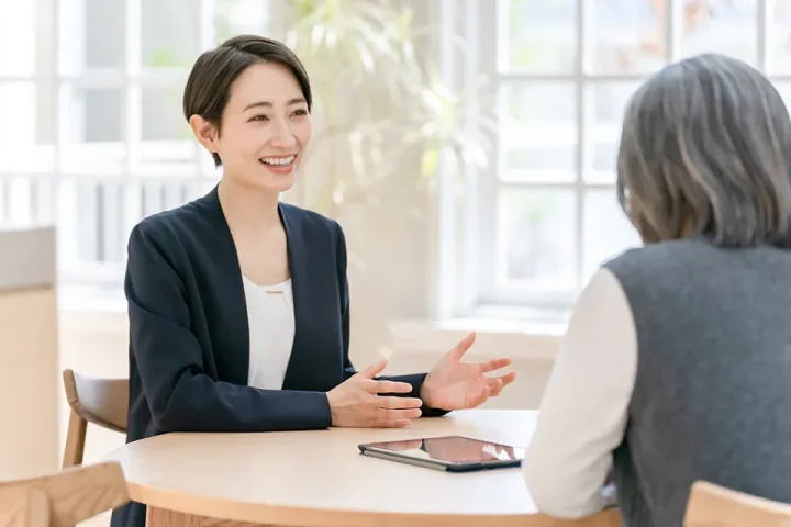 60代女性が仲人と向き合って婚活相談をしている背中越しの様子｜明るい相談室で安心して話せる雰囲気