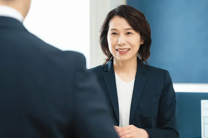 50代の女性仲人が会員と向き合い、婚活の相談に丁寧に応じている様子。地域密着型の結婚相談所KMAが提供する対面サポートの雰囲気を伝える面談シーン。