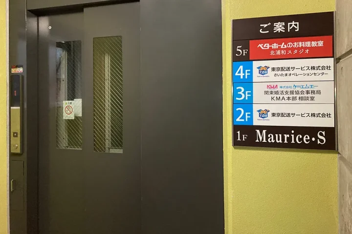 ATビル内のエレベーターホールと、各階のテナント案内板が見える様子