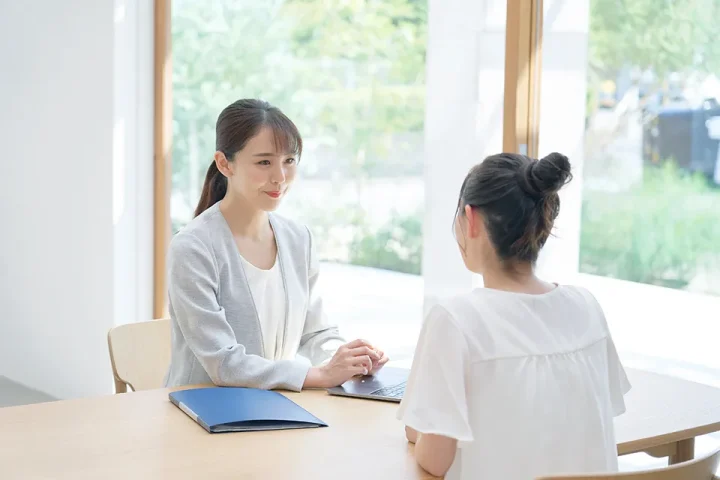 明るい相談室で仲人カウンセラーが穏やかな表情で面談者の相談に応じる様子