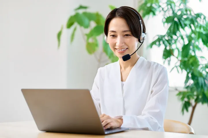 女性カウンセラーがインカムを付け、パソコン画面を見ながらLINE婚活相談に対応している様子