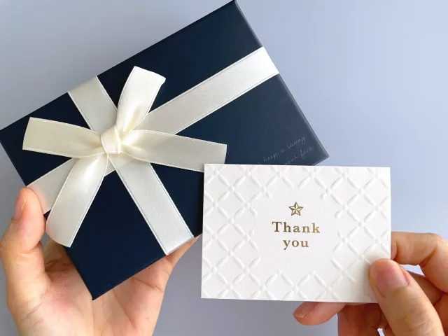 メッセージカードを添えたバレンタインチョコを手渡す女性の手元のイメージ写真