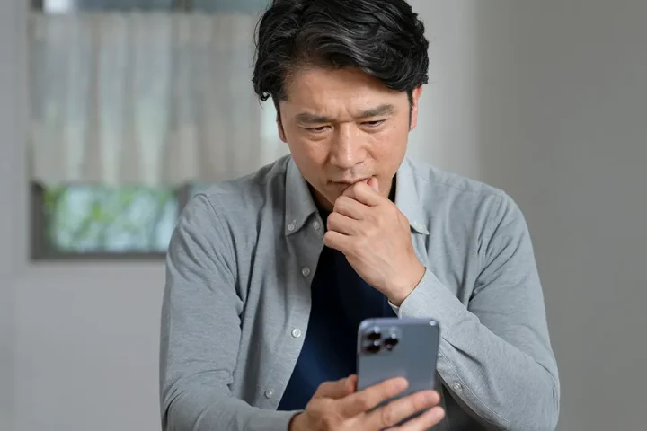 スマホを見て考え込む男性