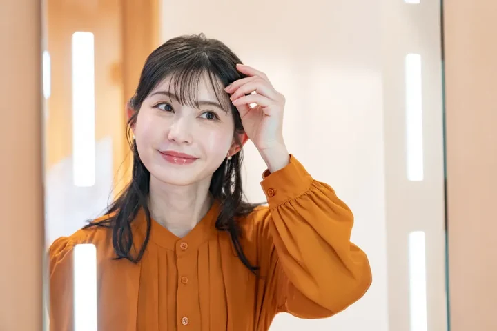 鏡を見て身支度する女性