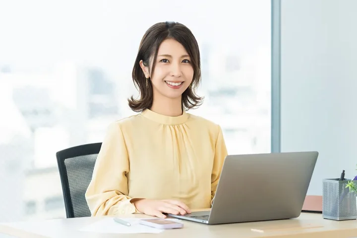 婚活プロフィールを見直しながら前向きに改善に取り組む女性。明るい室内でノートパソコンを見る姿が印象的