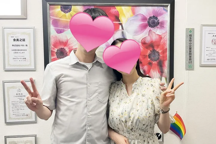 肩を抱き合いながらピースサインをする成婚カップル。顔はハートマークで隠れているが、笑顔と幸せな雰囲気が伝わるツーショット