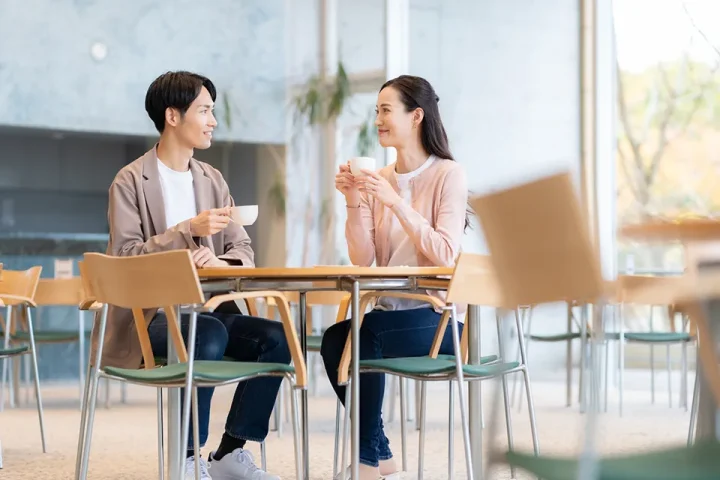 カフェで男性の話をにこやかに聞く女性の横顔と、穏やかな雰囲気のツーショット。