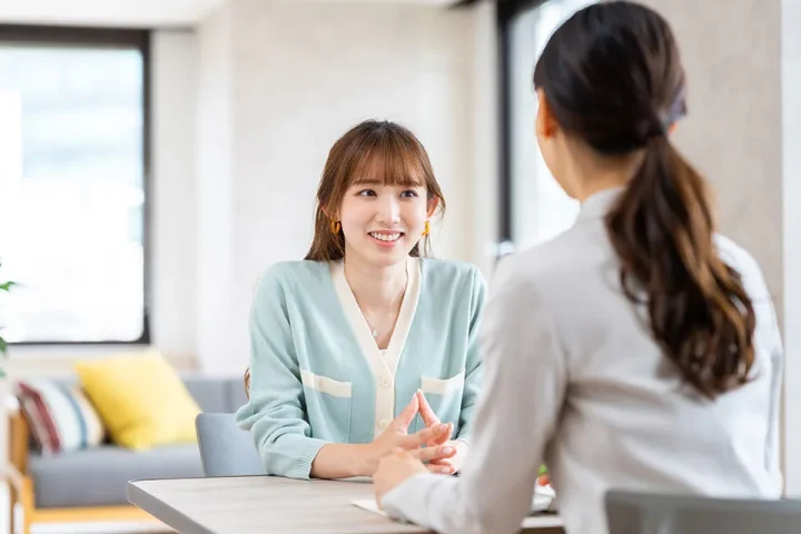 結婚相談所の無料相談で婚活カウンセラーの話を微笑みながら聞く相談者の様子