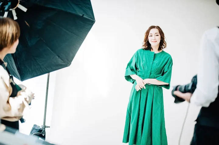 婚活プロフィール写真の撮影風景。カメラマンが女性を撮影し、助手がレフ版で光を調整している様子