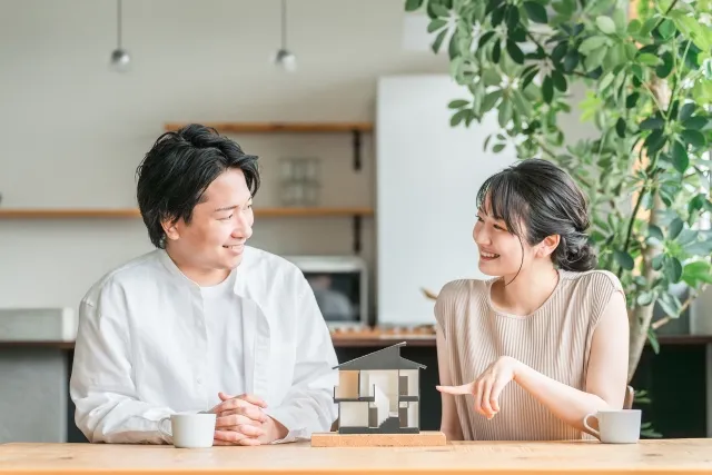 住宅模型を前に結婚後の生活を話し合うカップル