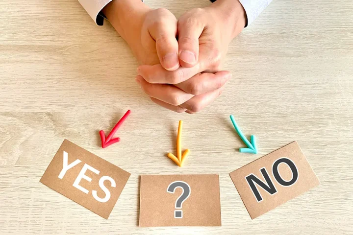 YES・NO・?カードを前に選択を迷う男性の手元