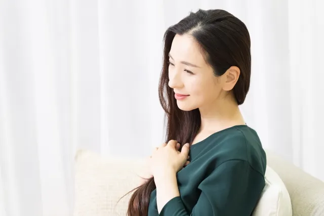 柔らかい光の中で胸に手を当てて微笑む女性のバストアップ写真｜自己肯定感を取り戻し前向きになるイメージ