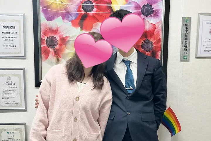 成婚退会手続きで来店したカップルが肩を寄せ合い、幸せそうに微笑む記念写真。顔はハートで隠されている。埼玉県さいたま市の結婚相談所KMA