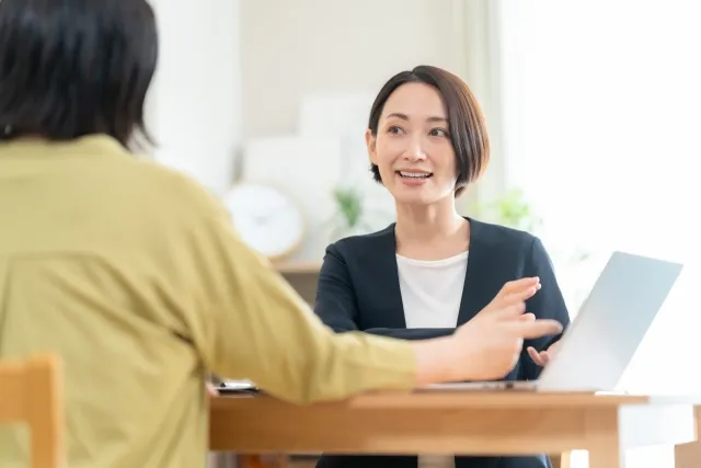 明るい室内でカウンセラーがパソコン画面を見せながら、優しい表情で受講者に個別セミナーを行っている様子。婚活の基礎を丁寧にレクチャーする場面。