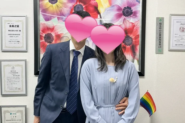 成婚退会手続きで来店したカップルが、顔をハートで隠して笑顔で寄り添う記念写真