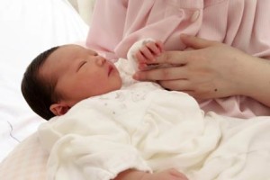 母の手を握る出産後の赤ちゃん