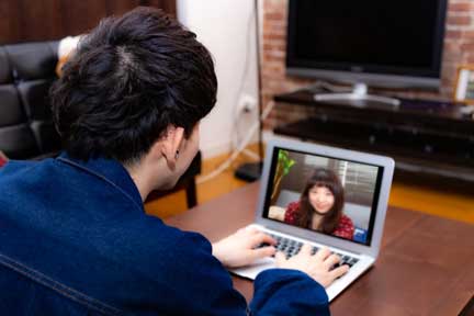 Zoomでオンラインお見合いをする男性の後ろ姿。パソコン画面に女性が映り、会話する様子がわかる写真