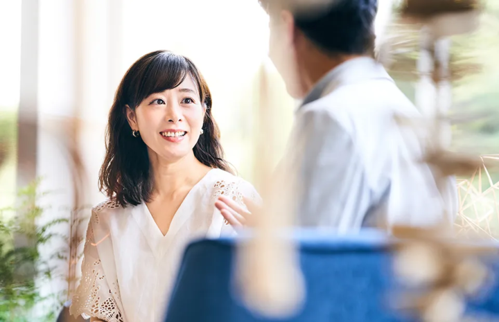 男性のボディランゲージを交えた会話を、にこやかな表情で聞く女性の様子｜お見合い当日の自然な振る舞いをイメージ
