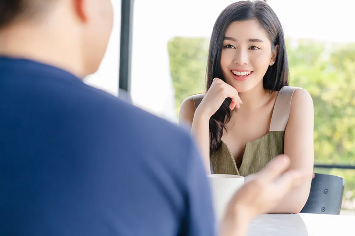 カフェラウンジで男性の話を聞き笑顔でうなずく女性