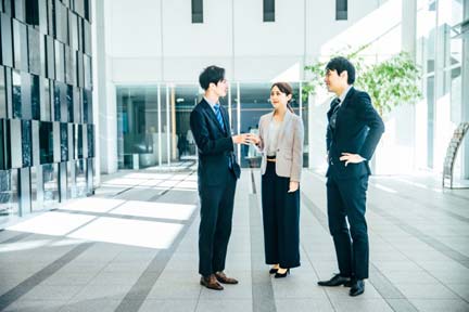 職場で面倒見のいい女性が部下の男性と雑談しながら笑顔でコミュニケーションを取る様子