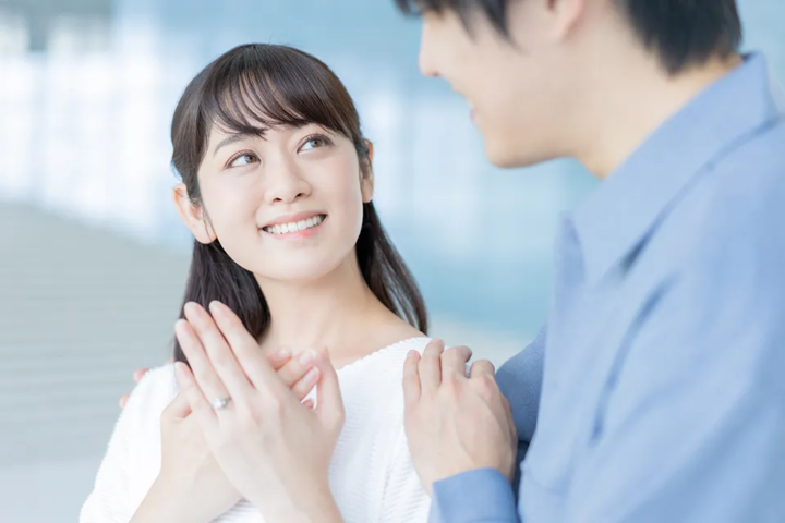 婚約指輪を胸の前にかざし、優しい表情で男性を見つめる30代女性の成婚イメージ