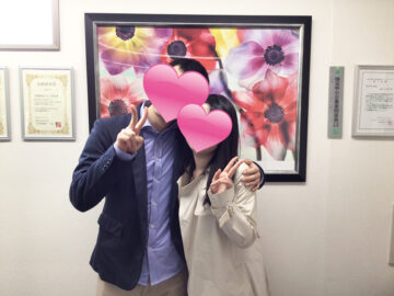 不思議なご縁で結ばれた成婚カップルが寄り添いピースサインをするツーショット写真（顔はハートで隠れている）